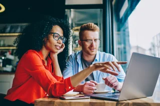 Two people pointing to sponsorships on a laptop