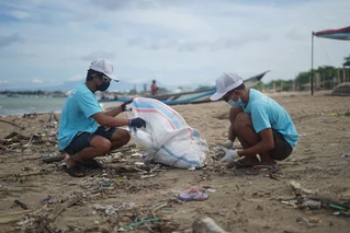 two people cleaning up beach